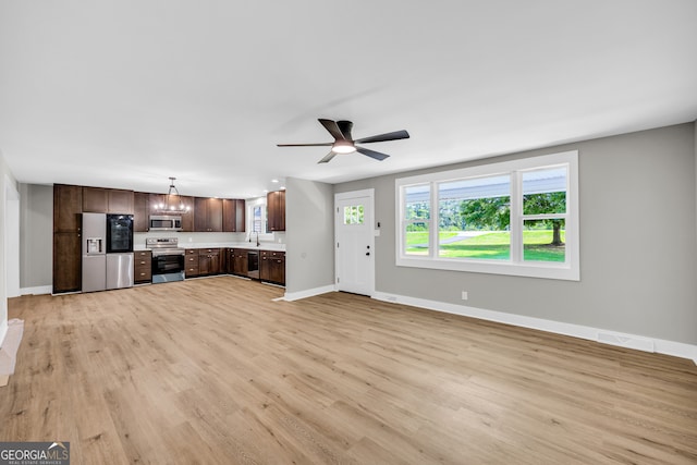 unfurnished living room featuring sink, ceiling fan with notable chandelier, and light wood-type flooring