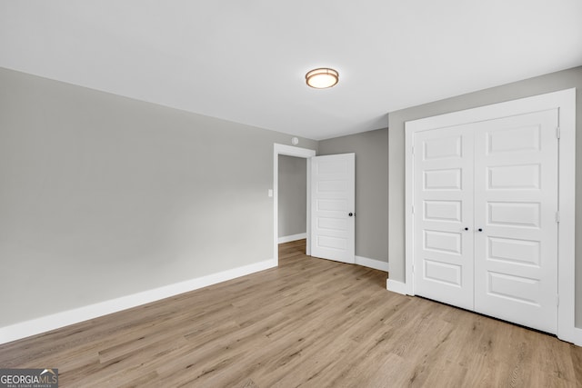 unfurnished bedroom with light hardwood / wood-style flooring and a closet