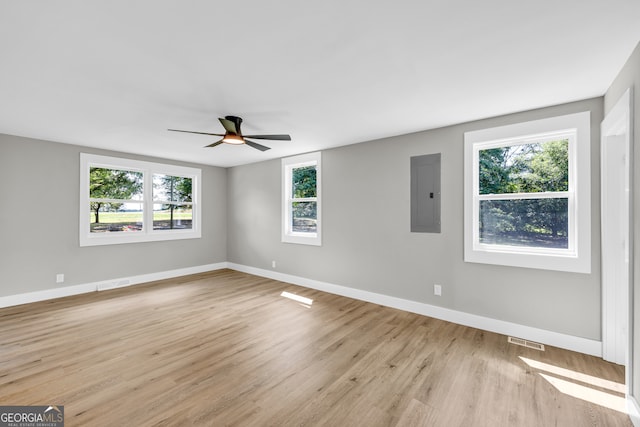 empty room with plenty of natural light, electric panel, ceiling fan, and light wood-type flooring