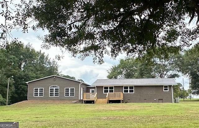 rear view of property featuring a wooden deck and a yard