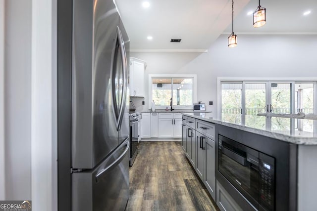 kitchen featuring light stone countertops, stainless steel appliances, dark wood-type flooring, pendant lighting, and white cabinets