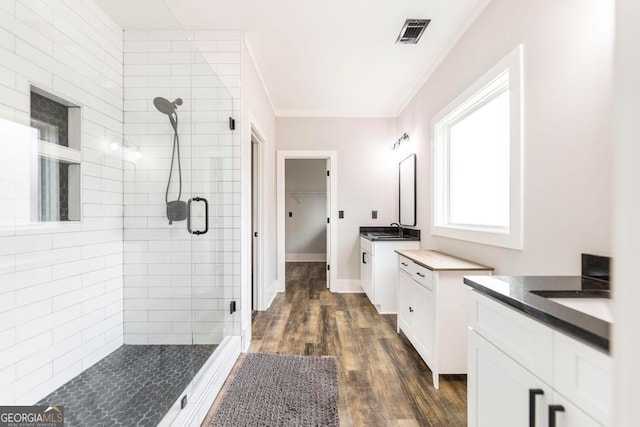 bathroom featuring wood-type flooring, vanity, walk in shower, and ornamental molding