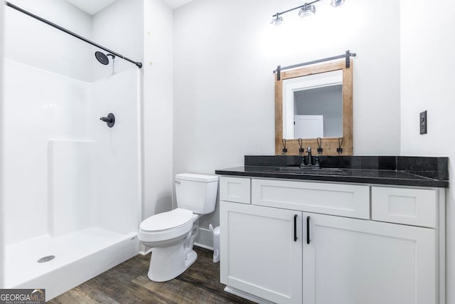 bathroom with hardwood / wood-style flooring, vanity, toilet, and a shower