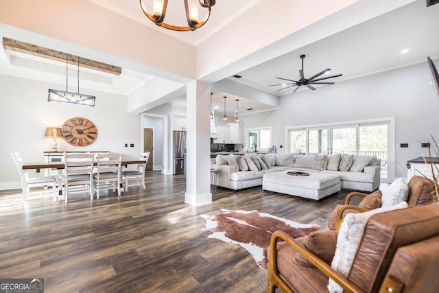 living room with dark hardwood / wood-style floors, ornamental molding, ceiling fan with notable chandelier, and a high ceiling