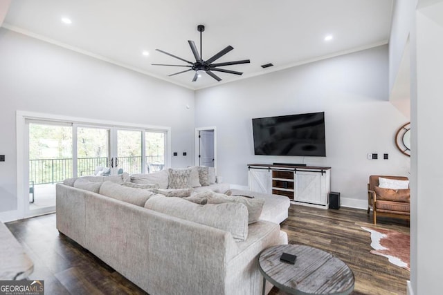 living room with ceiling fan, dark hardwood / wood-style flooring, ornamental molding, and a towering ceiling