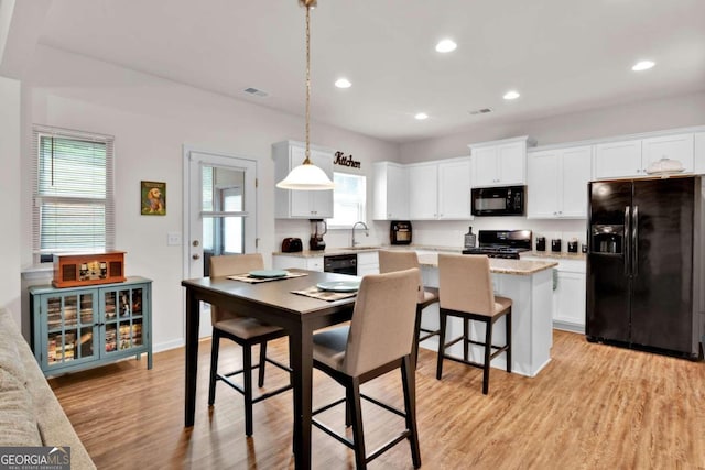 kitchen featuring a center island, black appliances, decorative light fixtures, light hardwood / wood-style floors, and white cabinetry