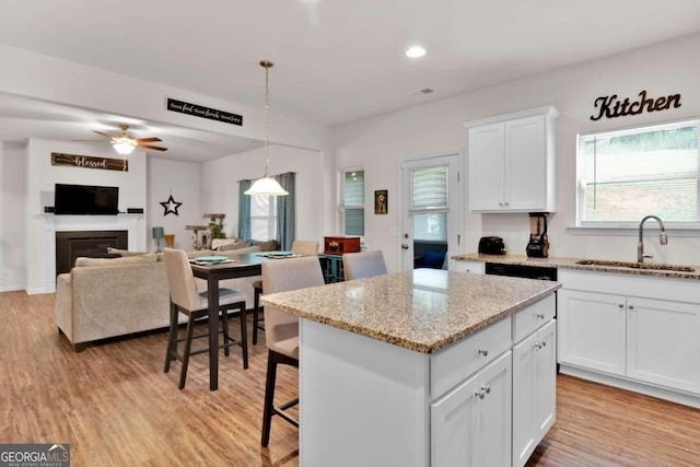 kitchen featuring a center island, white cabinets, sink, decorative light fixtures, and light hardwood / wood-style floors