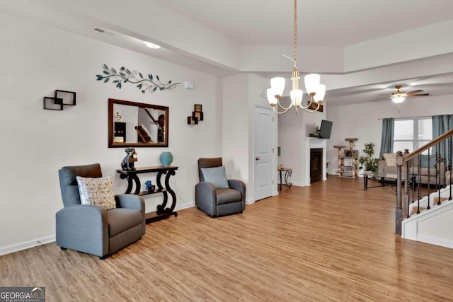 living area featuring hardwood / wood-style floors and ceiling fan with notable chandelier