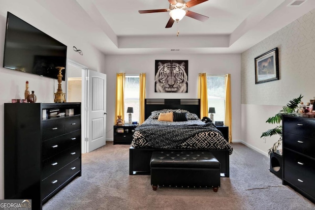 carpeted bedroom featuring ceiling fan and a tray ceiling