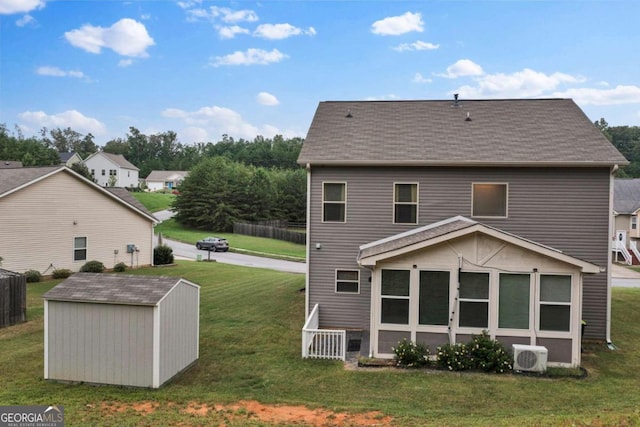 rear view of house with a lawn, ac unit, and a shed