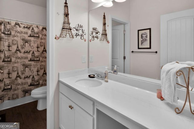 bathroom featuring wood-type flooring, vanity, toilet, and curtained shower