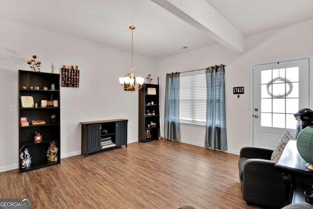 living area with beam ceiling, a notable chandelier, and hardwood / wood-style flooring