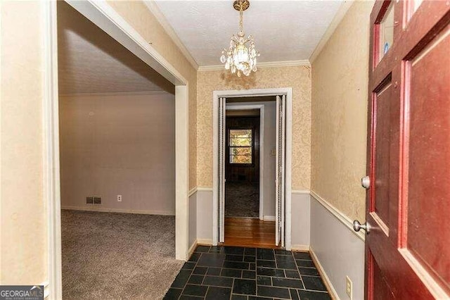 interior space with an inviting chandelier, dark carpet, and ornamental molding