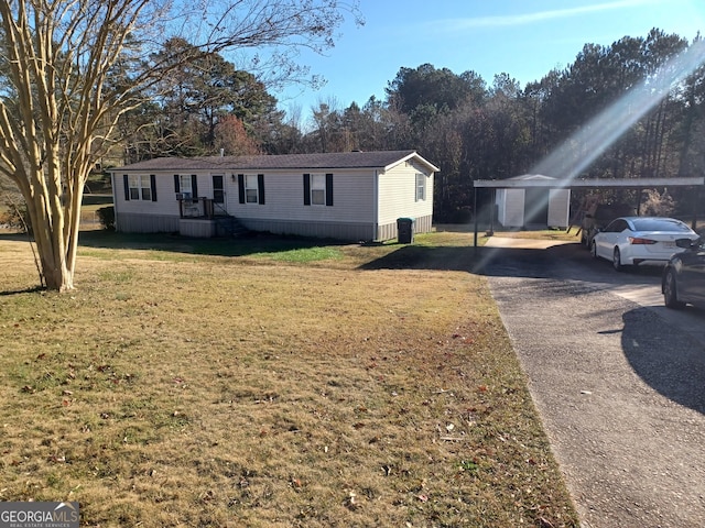 manufactured / mobile home featuring a carport and a front yard