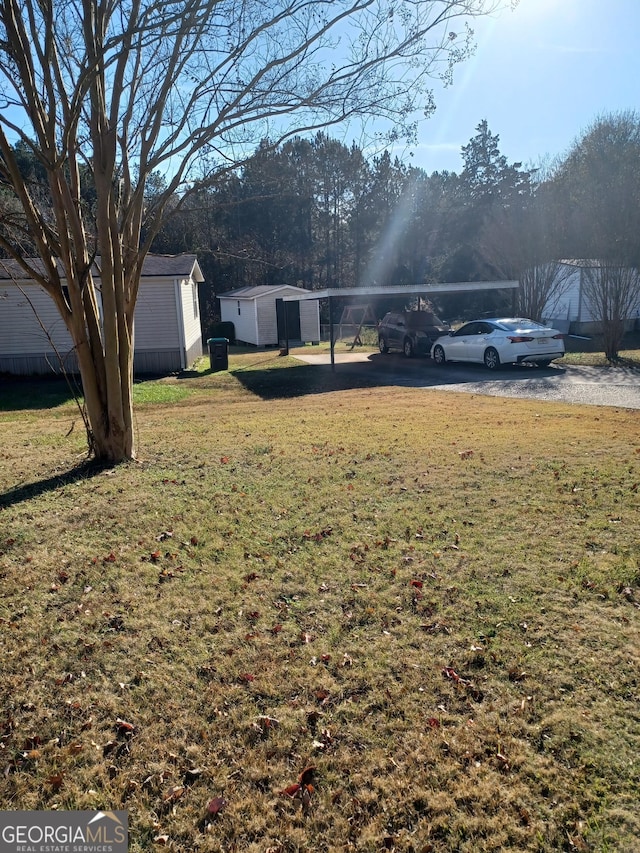 view of yard featuring an outdoor structure, a detached carport, a shed, and gravel driveway