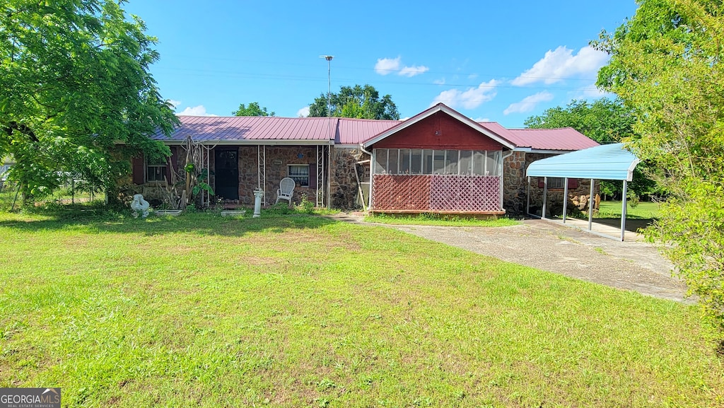 view of front of home with a carport, a sunroom, and a front yard