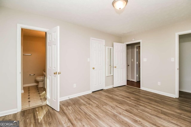 unfurnished bedroom featuring wood-type flooring and ensuite bath