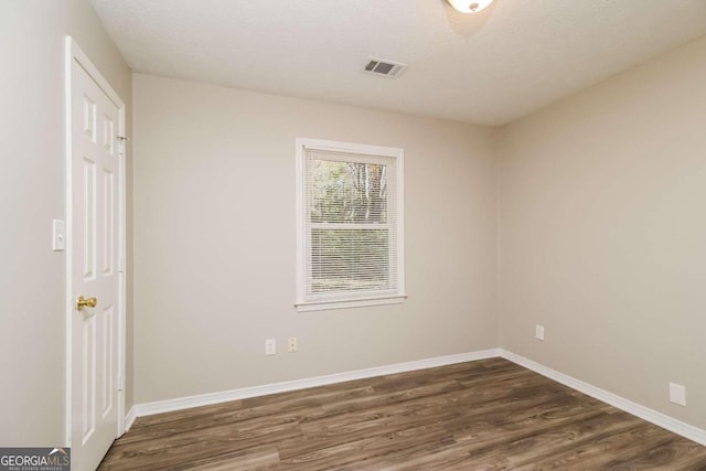 empty room with a textured ceiling and dark wood-type flooring