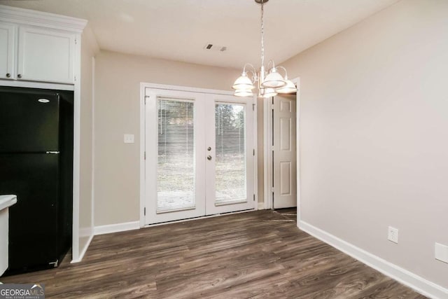 unfurnished dining area with a chandelier, french doors, and dark wood-type flooring