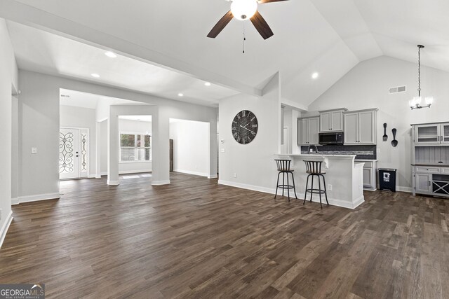 unfurnished living room featuring dark hardwood / wood-style flooring, ceiling fan with notable chandelier, and vaulted ceiling