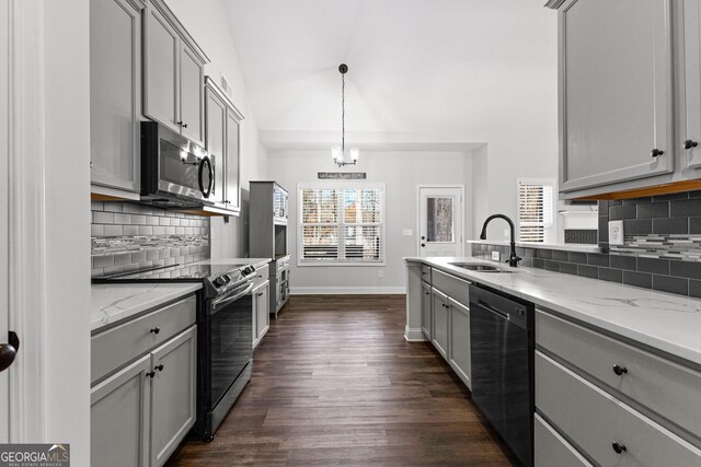 kitchen with sink, gray cabinets, light stone countertops, appliances with stainless steel finishes, and dark hardwood / wood-style flooring