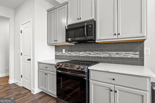 kitchen with gray cabinetry, decorative backsplash, light stone countertops, electric range oven, and dark hardwood / wood-style flooring