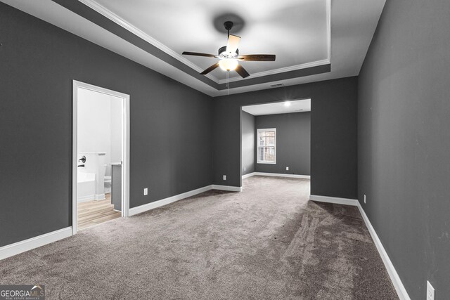 carpeted spare room featuring a raised ceiling, crown molding, and ceiling fan