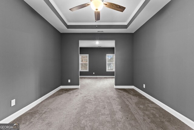 carpeted spare room featuring a tray ceiling, crown molding, and ceiling fan