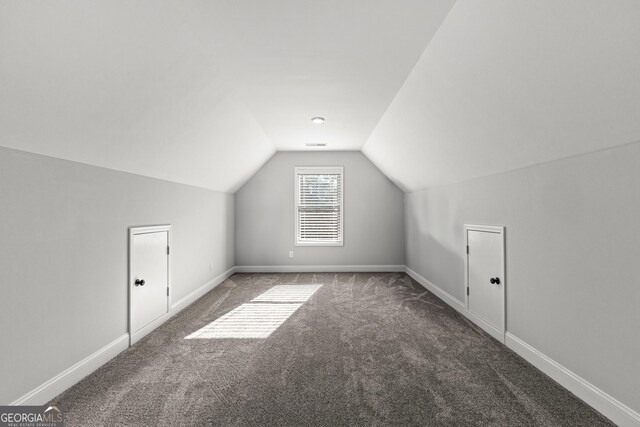 additional living space with vaulted ceiling and dark colored carpet