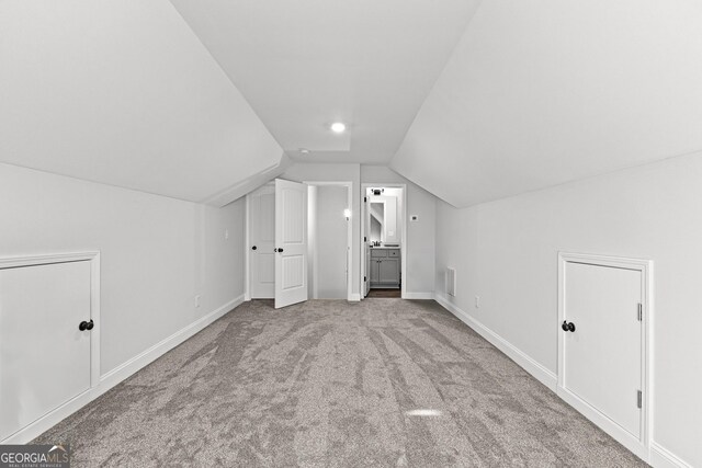 bonus room with light carpet and vaulted ceiling