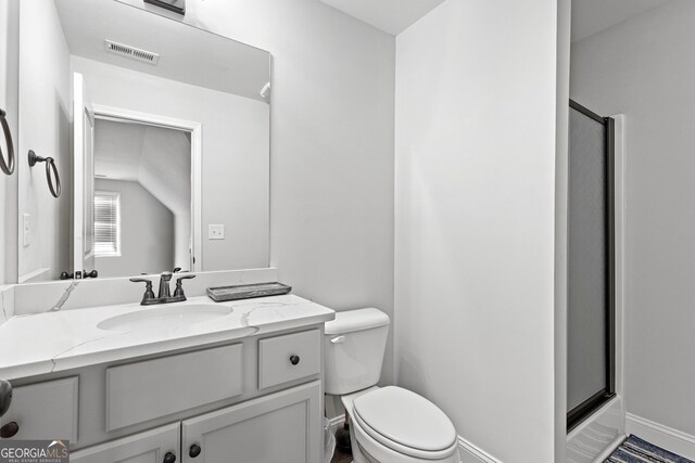 bathroom with vanity, toilet, and a shower with shower door