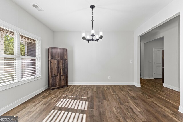 unfurnished dining area featuring dark hardwood / wood-style flooring and an inviting chandelier