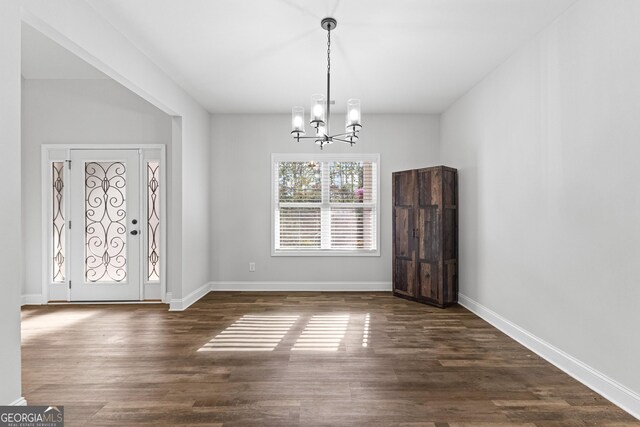 foyer with dark wood-type flooring and an inviting chandelier