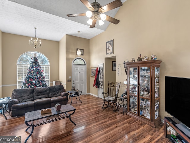 living room featuring ceiling fan with notable chandelier, a textured ceiling, dark hardwood / wood-style flooring, and high vaulted ceiling