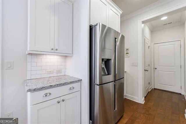 kitchen featuring light stone countertops, dark hardwood / wood-style flooring, stainless steel refrigerator with ice dispenser, white cabinets, and ornamental molding