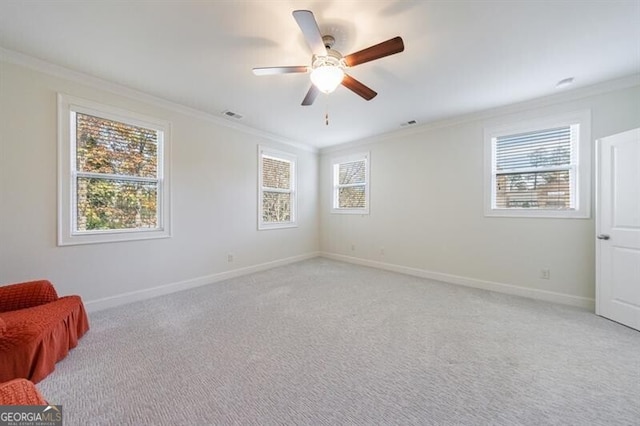 carpeted empty room featuring plenty of natural light, ceiling fan, and crown molding