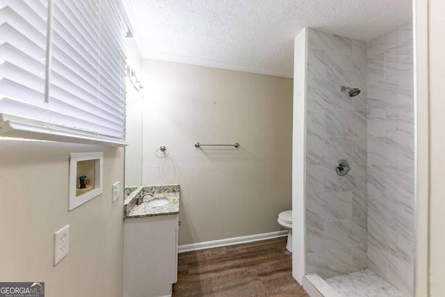 bathroom featuring tiled shower, wood-type flooring, vanity, and a textured ceiling