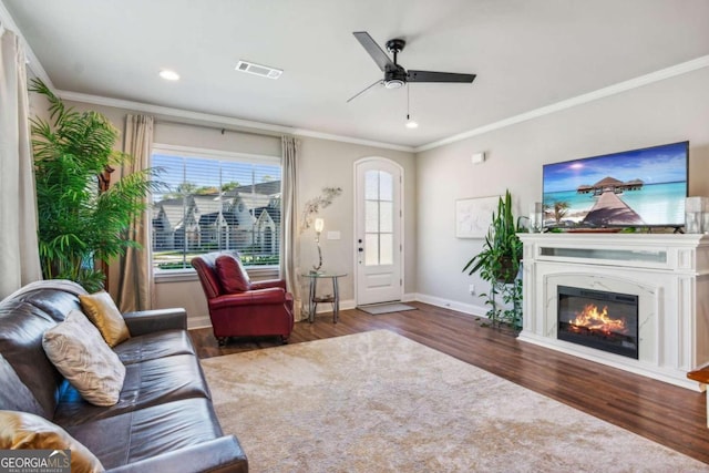 living room with crown molding, dark hardwood / wood-style flooring, a high end fireplace, and ceiling fan