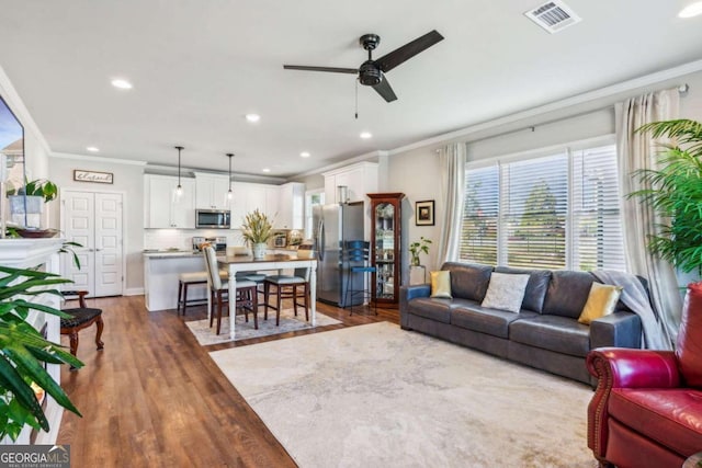 living room with ceiling fan, ornamental molding, and dark wood-type flooring