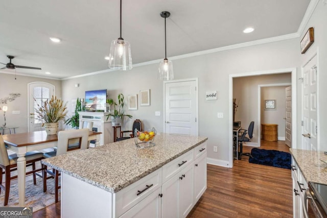 kitchen featuring white cabinetry, a center island, dark wood-type flooring, decorative light fixtures, and ornamental molding