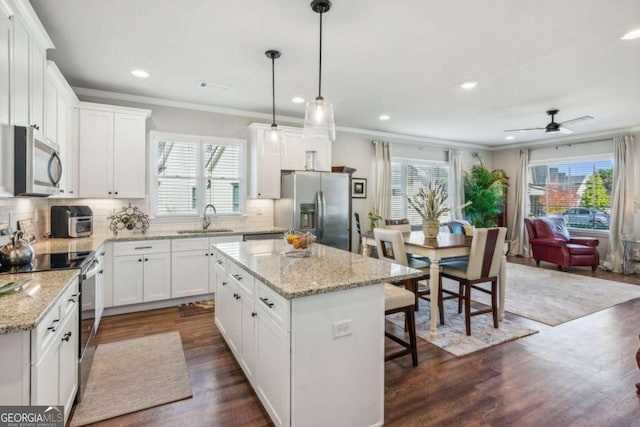 kitchen featuring stainless steel appliances, a kitchen island, a healthy amount of sunlight, and sink