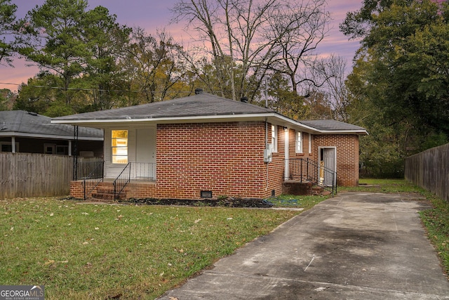 view of front of property featuring crawl space, brick siding, a front yard, and fence