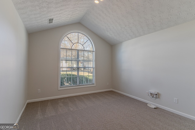 empty room featuring carpet flooring, a textured ceiling, and vaulted ceiling