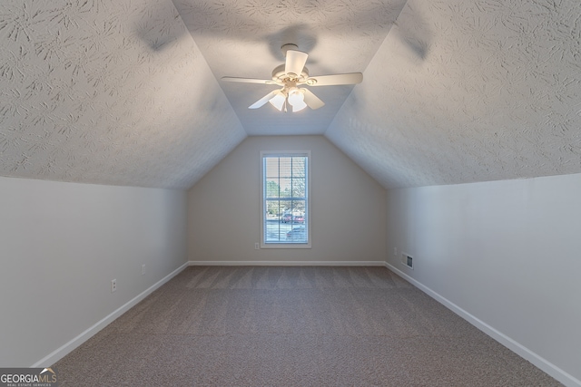 additional living space featuring a textured ceiling, carpet floors, vaulted ceiling, and ceiling fan