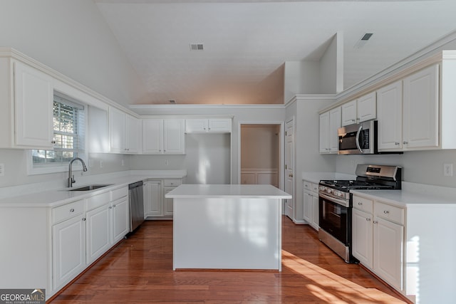 kitchen with hardwood / wood-style floors, sink, appliances with stainless steel finishes, a kitchen island, and white cabinetry