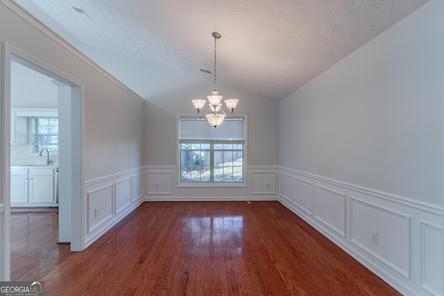 unfurnished dining area featuring a chandelier, plenty of natural light, dark hardwood / wood-style floors, and vaulted ceiling