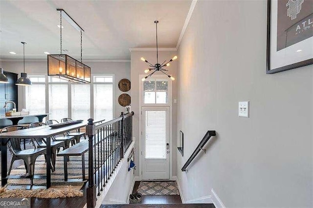 foyer featuring dark hardwood / wood-style flooring, crown molding, and a chandelier