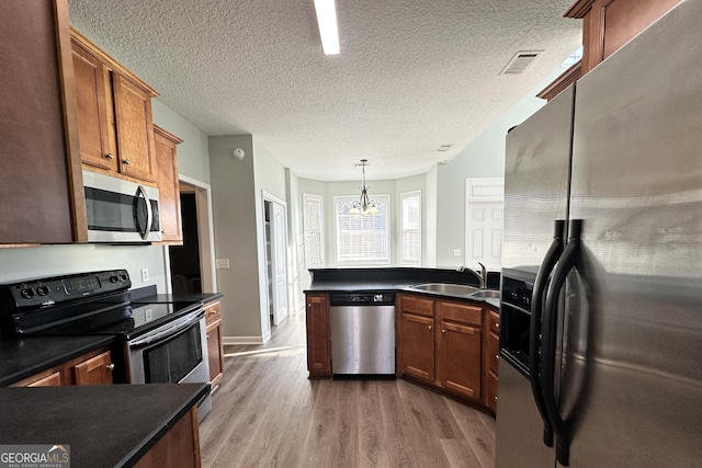 kitchen with sink, hardwood / wood-style flooring, decorative light fixtures, stainless steel appliances, and a chandelier