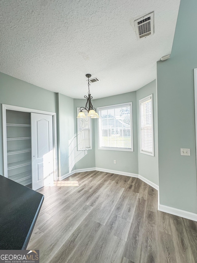 unfurnished dining area featuring a textured ceiling and hardwood / wood-style flooring