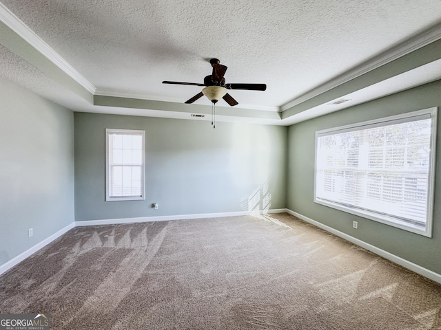 carpeted empty room with ceiling fan, a raised ceiling, ornamental molding, and a textured ceiling